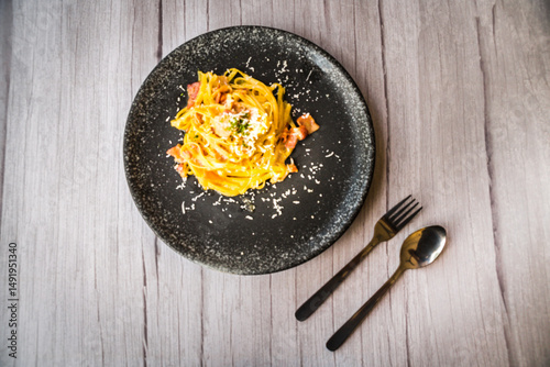 Carbonara with ham cream and cheese served on a black plate