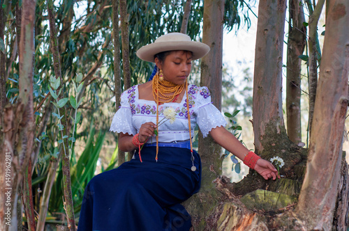 Indigenous otavalo girl wearing traditional clothes holding flowers in ecuadorian forest