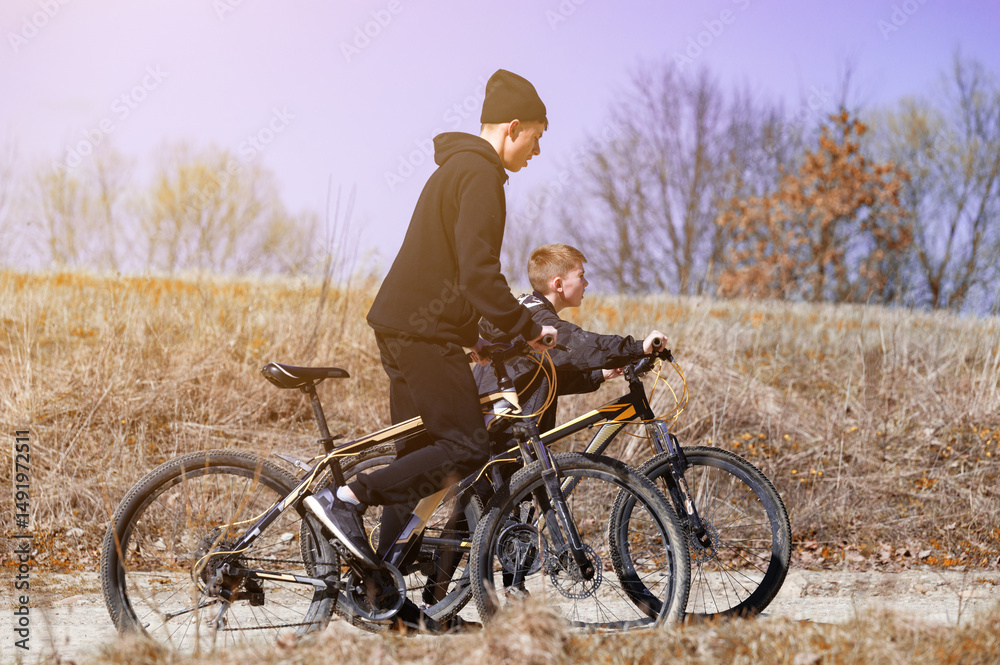 Fototapeta premium Two boys enjoy a sunny bike ride through a field, enjoying the fresh air and the beautiful scenery.