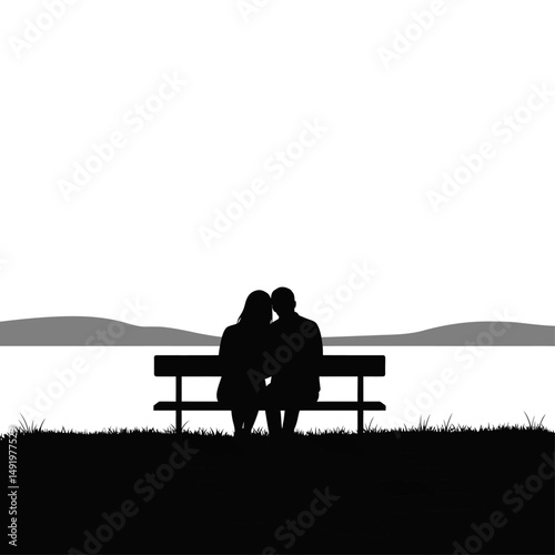 Silhouette of a couple sitting on a bench looking at a lake with mountains in the background view