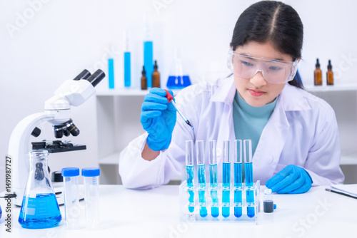 Scientist girl uses dropper to carefully handle blue chemical samples in a lab. Science, laboratory, scientist, experiment, and research reflect focus and precision in learning, healthcare.