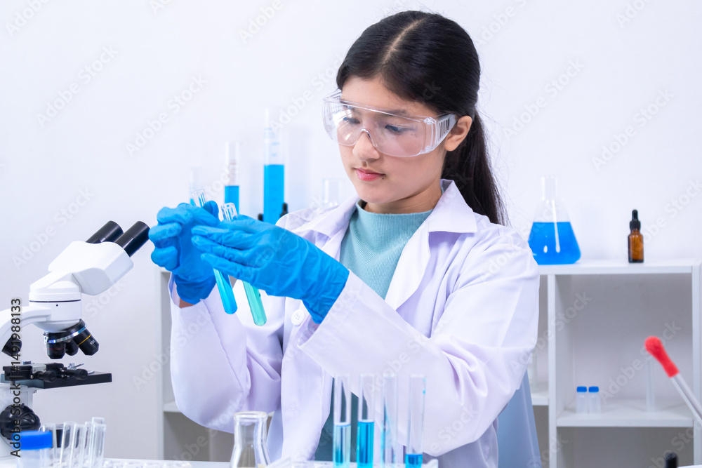 Fototapeta premium A teenage girl scientist in a laboratory carefully inspects liquid sample in pipette while wearing gloves and lab coat, involved in science, laboratory, scientist, experiment, and research, health.