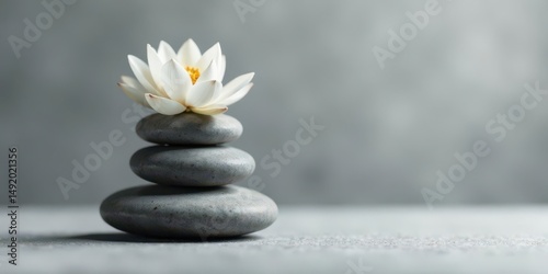 Serene Stack of Smooth Grey Stones Topped with a Delicate White Flower, Evoking Tranquility and Inner Peace