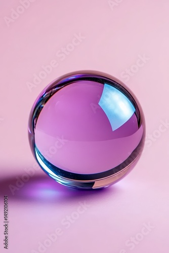 Reflective glass sphere on soft pink background