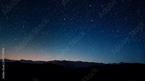 a a movement of stars in the night sky with the view of mountains.