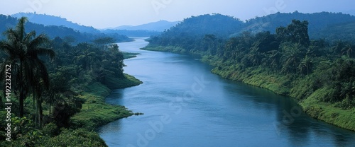 Obraz na płótnie Serene river meanders through lush green landscape. Tranquil waters reflect sky w salonie