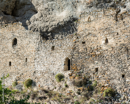 ruined facade of an ancient building In North Ossetia Russia Caucasus Ancient stone wall with small windows.