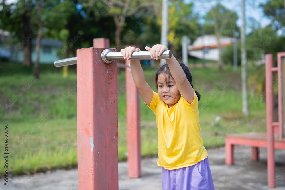 Obraz premium Asian Young Girl Engaging in Outdoor Physical Activity at Playground, Focused on Strength Training and Fitness, Promoting Healthy Active Lifestyle for Children