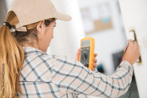 woman testing a light switch with a multimeter