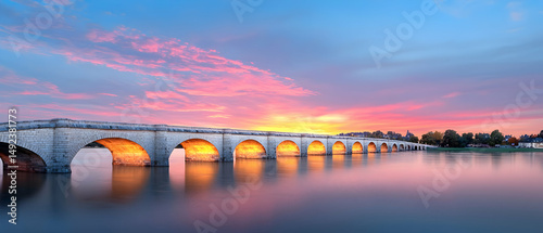 Historic Stone Bridge At Sunset Over Calm River