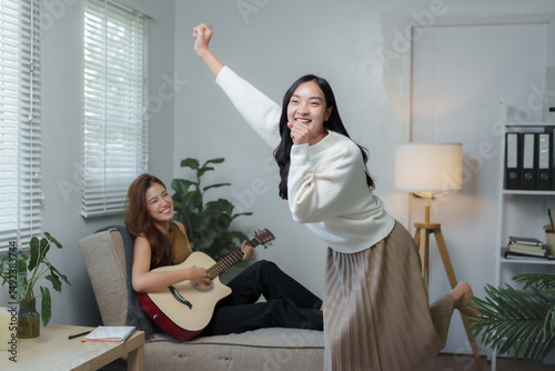 Young women playing guitar and dancing at home
