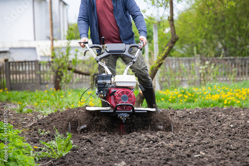 Принти на полотні Farmer using tiller on a plowed field