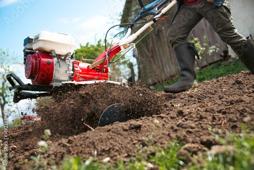 Farmer using tiller on a plowed field