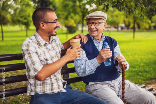 Portrait of happy grandfather and grandson in park. They are spending time together and having fun.