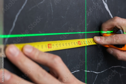 Wallpaper Mural hands of a worker who measures the width of a tabletop with a tape measure and a laser Torontodigital.ca