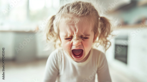 Upset toddler girl crying loudly indoors, face expressing strong emotion.