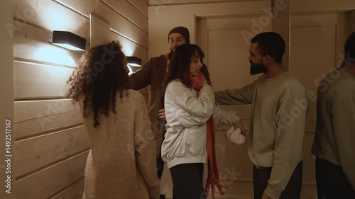 Two couples say goodbye to each other and hug while one stands in the hallway and the other leaves