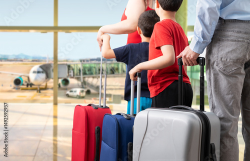 Travelers and families with luggage while waiting in line to board at the airport. Emphasis on carry-on and wheeled luggage.