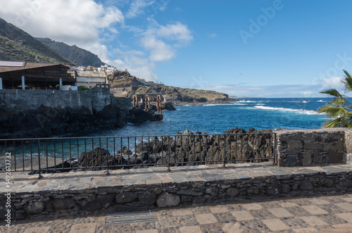 Old fish factory building at center of Garachico old town with sea pools and lava rocks at Tenerife canary island, Spain. Blue sky white clouds background