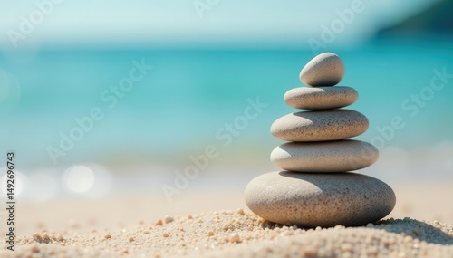 Perfectly balanced pebble pyramid on sandy beach, calm sea backdrop, serenity, photography