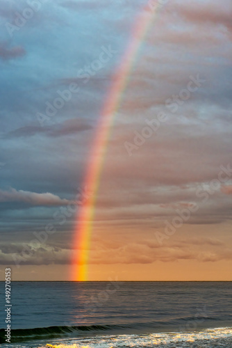 A shining rainbow in the gloomy sky over the sea. Low clouds over the water in the bay.