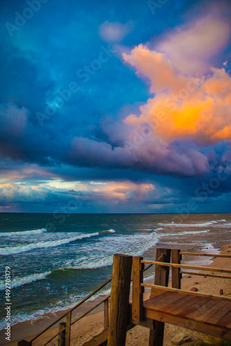 Dark sky over the sea. Low clouds over the water in the bay. Background with a tense panorama of the coast before a storm at sunset.