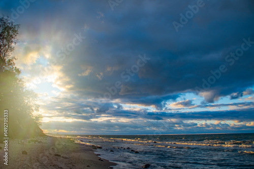 Dark sky over the sea. Low clouds over the water in the bay. Background with a tense panorama of the coast before a storm at sunset.