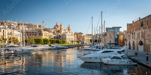 Spectacular view of the moored sailing yachts in seaport Vittoriosa and St. Lawrence's Catholic Church. Location place Birgu harbour, Malta, Europe. Photo wallpapers. Golden hour.