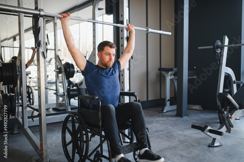 Man with disability lifting weights in wheelchair at gym for rehabilitation and sports training