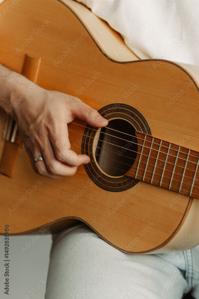 Fototapeta premium Close-up of a person's hands playing an acoustic guitar