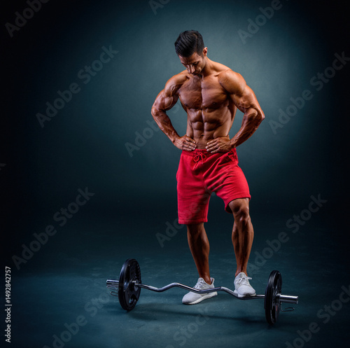 Muscular Man Posing in front of Barbell 