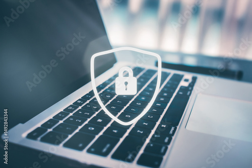 Laptop with a shield icon on an office desk. Concept of cyber security and data protection