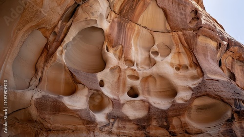 Mesa sandstone cliffs honeycomb weathering with sculpted cavities and natural erosion patterns in amber and cream tones under natural lighting