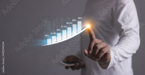 Young man with smartphone hand touching to visualize money growth The phone screen displays graphs and charts showing increasing investment and savings trends, along with an increased account balance