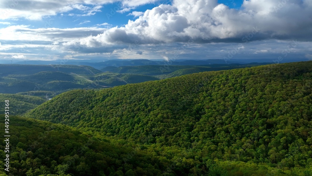 Obraz premium Rolling green hills and mountains under blue sky with clouds in early morning sunlight in West Virginia Mountains