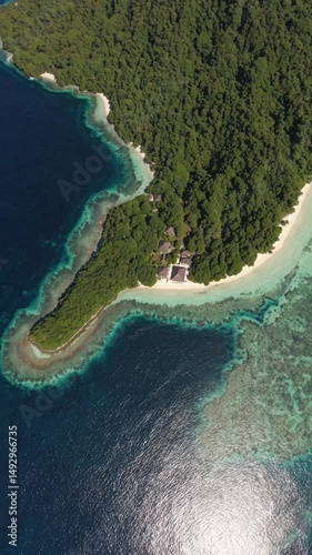 An aerial view of a secluded island with pristine white sand beach, surrounded by turquoise waters. Lush green foliage covers most of the island, creating a stunning contrast against the ocean blue
