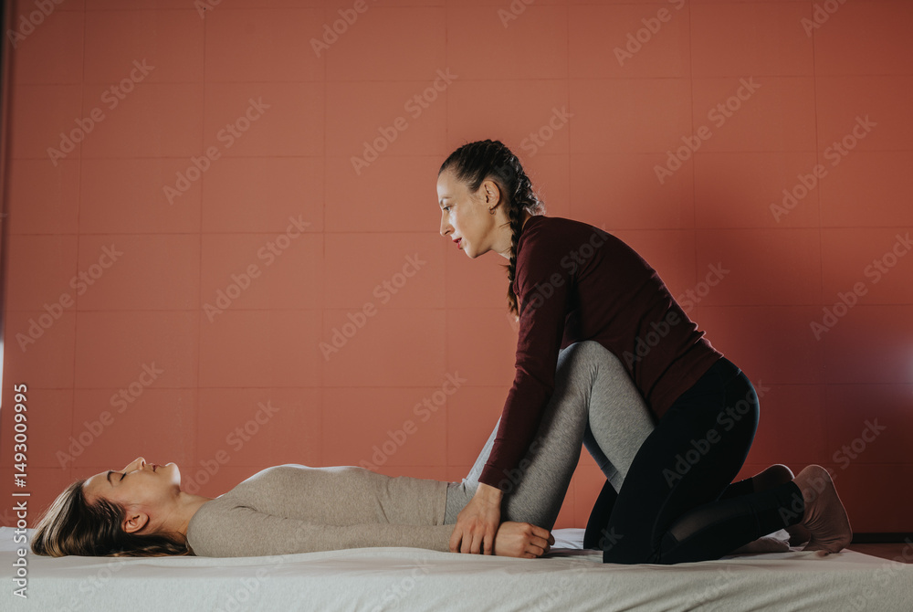 Obraz premium A wellness expert provides a therapeutic stretch to a person, promoting relaxation and well-being. The setting features a serene ambiance with care and focus on health and physical improvement.