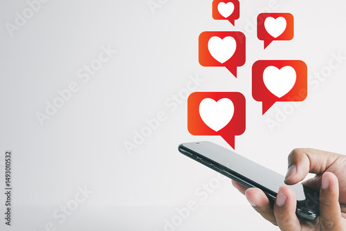Close-up view of a hand holding a smartphone with floating heart reaction icons symbolizing social media engagement,online interactions,digital marketing and communication.