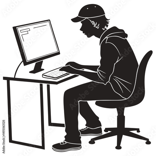 Silhouette of a young man working at a computer on a desk
