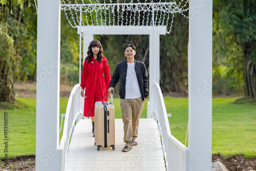 Beautiful young happy couple of tourists walking with luggage at countryside homestay surrounded by green forest Concept of people and healthy natural lifestyle.