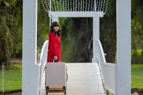 Asian woman walking with suitcase through wooden white bridge, enjoying vacation getaway enjoying nature breathing fresh air. Travel, tourism, leisure, destination, exploration, adventure