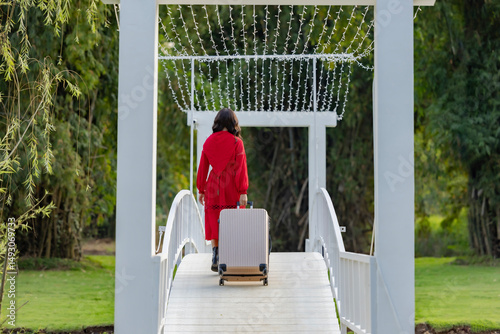 Back view of Young woman with suitcase in hand going away by countryside or homestay with mountain view in sunny day.
