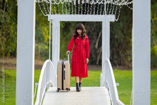 Happy traveler pulling her suitcase while walking on wooden bridge at exotic resort and enjoy the scenery view.