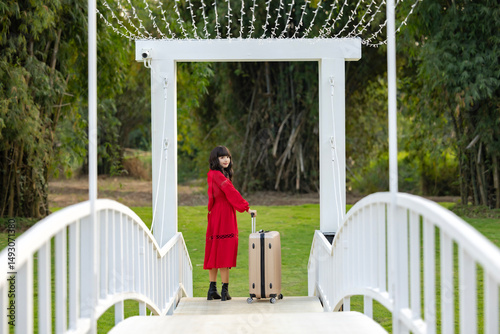 
Smiling asian businesswoman walking with luggage at countryside homestay surrounded by green forest Concept of people and healthy natural lifestyle.