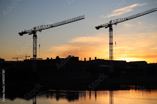 Sunset cityscape featuring silhouettes of construction cranes against a glowing sky, Porvoo, Finland