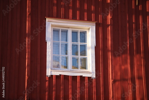 Close-up of the facade of a red-painted wooden building in classic Scandinavian style, featuring a window with crisp white frames, Porvoo, Finland