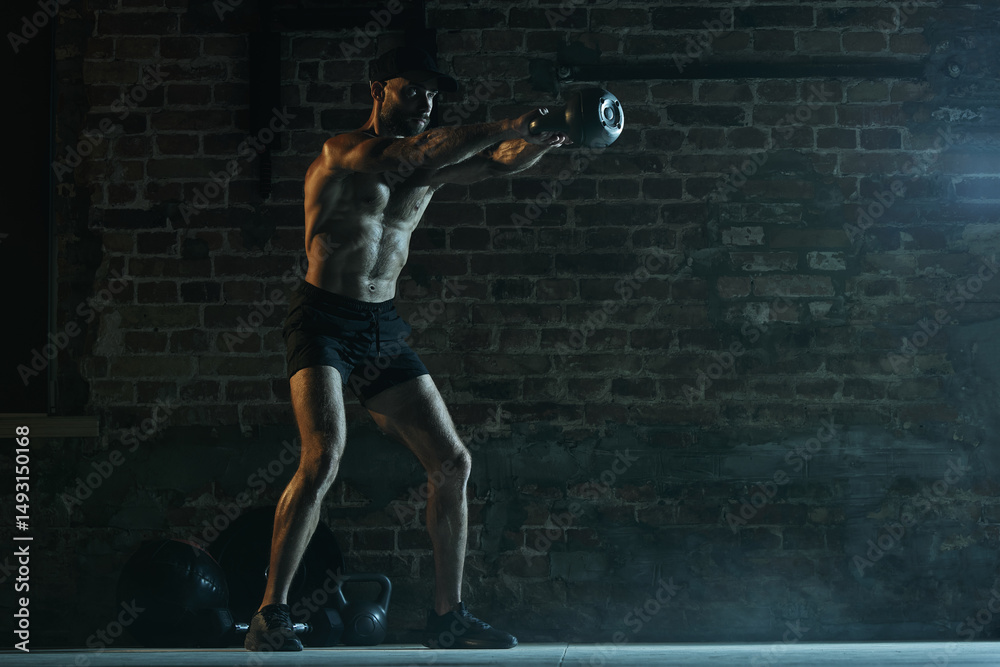 Shirtless man doing kettlebell swing with arms extended in gym showing core tension and control. Concept of gym training, physical strength, movement, focus and lifestyle activity. Shirtless man doing kettlebell swing with arms extended in gym showing core tension and control. Concept of gym training, physical strength, movement, focus and lifestyle activity.