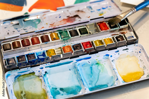 Paintbrush resting on a used watercolor palette