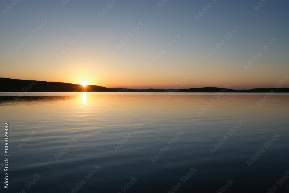 Obraz premium Serene moment of sunset over a peaceful lake