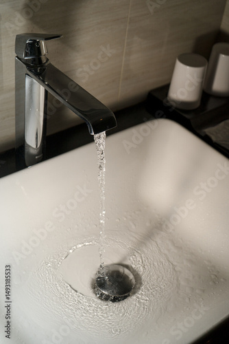 Shiny faucet with water flowing in a clean bathroom sink